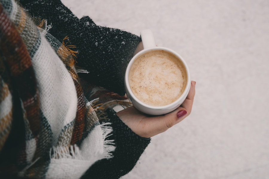 A lady holding a cup of coffee in a cold weather