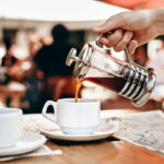 An image of a person pouring a less acidic coffee from a french press