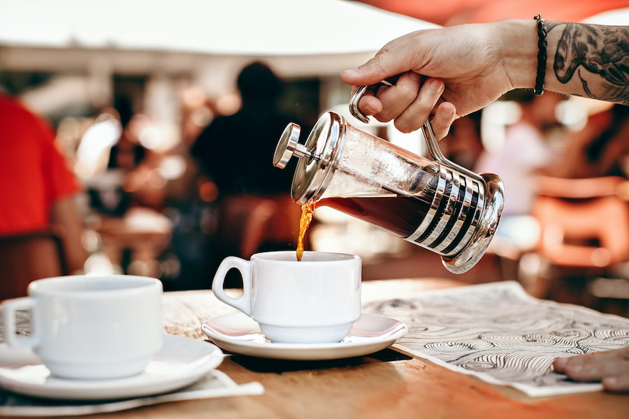 An image of a person pouring a less acidic coffee from a french press