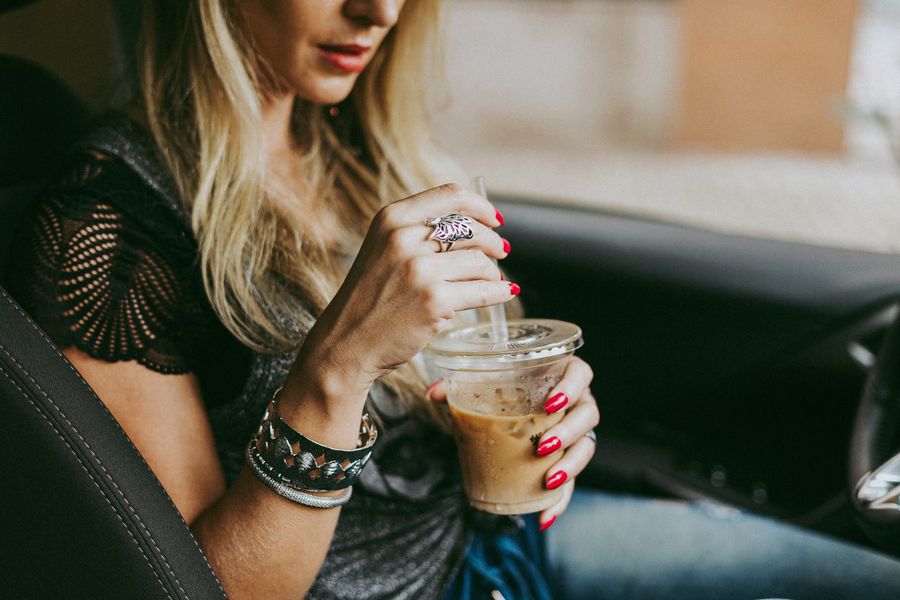 Woman drinking her iced coffee on the car