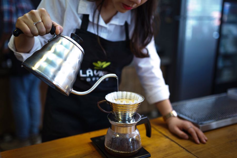 Barista using a gooseneck kettle to pour over coffee
