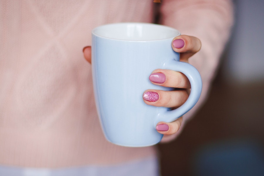 Female with pink nail polish holding the coffee cup