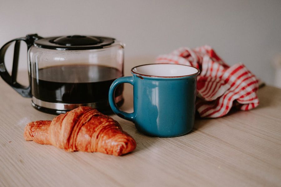 Croissant, coffee pot and mug on a table