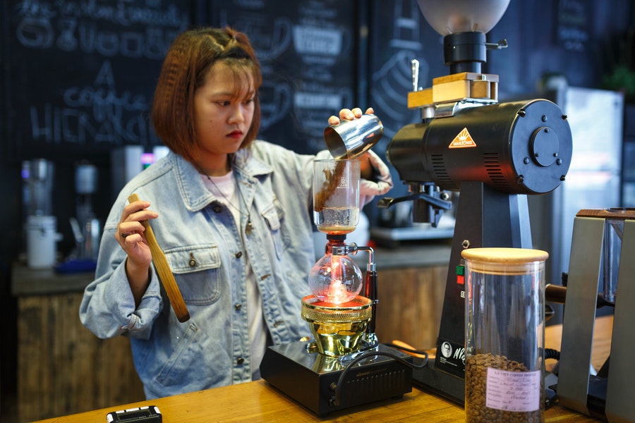 Girl in denim pouring some coffee grounds