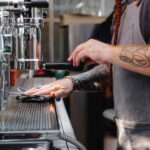 An image of a barista wiping the coffee machine