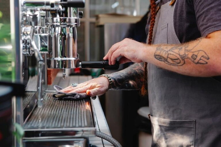 An image of a barista wiping the coffee machine