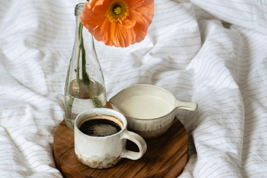 An image of coffee and milk with flower vase on a tray