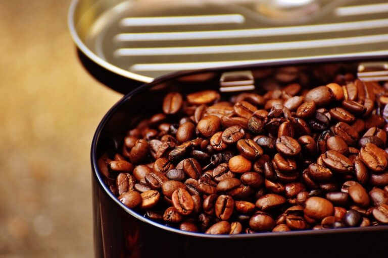 Roasted coffee beans in a black metal tin can on a brown surface